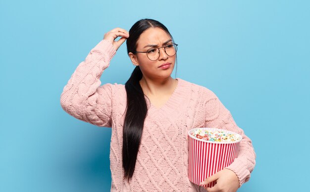 Hispanic woman feeling puzzled and confused, scratching head and looking to the side