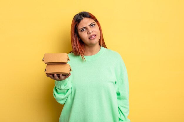 히스패닉계 여성은 어리둥절하고 혼란스러워합니다. 햄버거 개념을 테이크 아웃