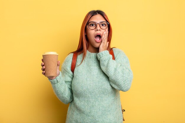 Hispanic woman feeling shocked and scared. student with a coffee concept