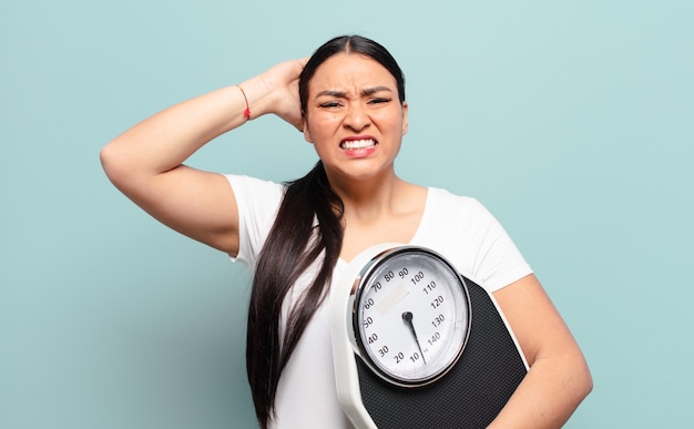 Hispanic woman feeling stressed, worried, anxious or scared, with hands on head, panicking at mistake