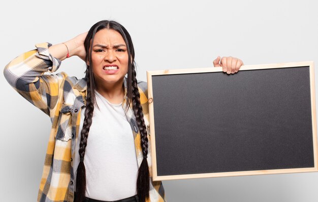 Hispanic woman feeling stressed, worried, anxious or scared, with hands on head, panicking at mistake