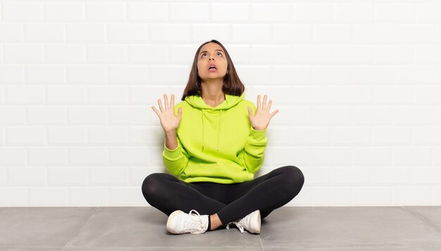 Hispanic woman feeling stupefied and scared, fearing something frightening, with hands open up front saying stay away