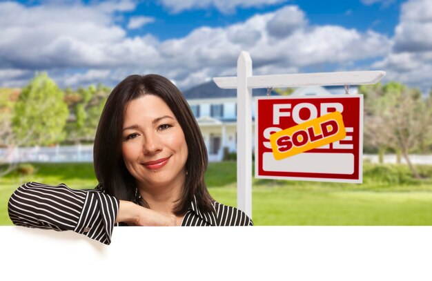 Photo hispanic woman in front of sold for sale sign house