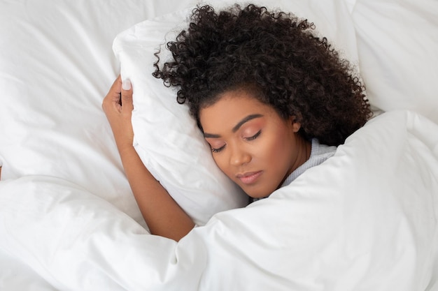 hispanic woman is peacefully sleeping in a bed with white sheets she is lying comfortably with her