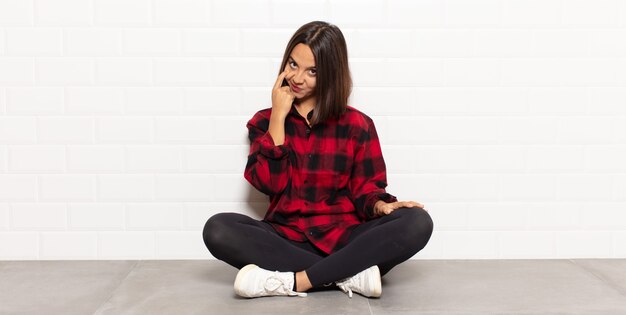 Hispanic woman keeping an eye on you, not trusting, watching and staying alert and vigilant