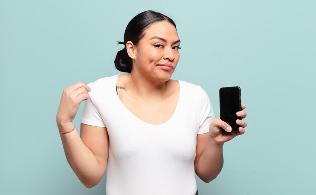 Hispanic woman looking arrogant, successful, positive and proud, pointing to self