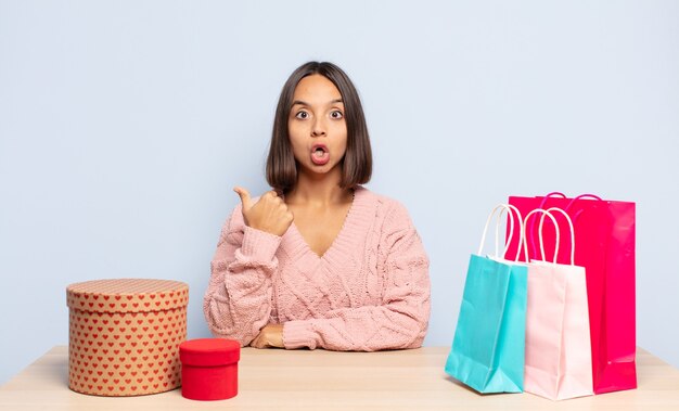 Hispanic woman looking astonished in disbelief, pointing at object on the side and saying wow, unbelievable