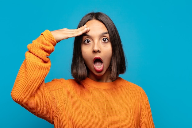 Hispanic woman looking happy, astonished and surprised, smiling and realizing amazing and incredible good news