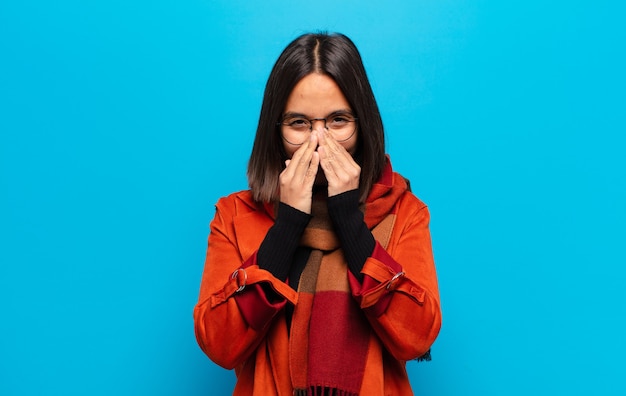 hispanic woman looking happy, cheerful, lucky and surprised covering mouth with both hands