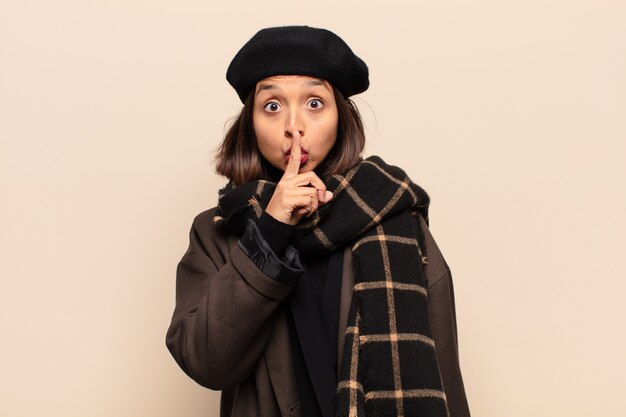 Hispanic woman looking serious and cross with finger pressed to lips demanding silence or quiet, keeping a secret