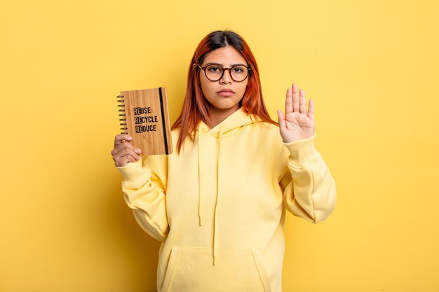 Hispanic woman looking serious showing open palm making stop gesture. recycle concept