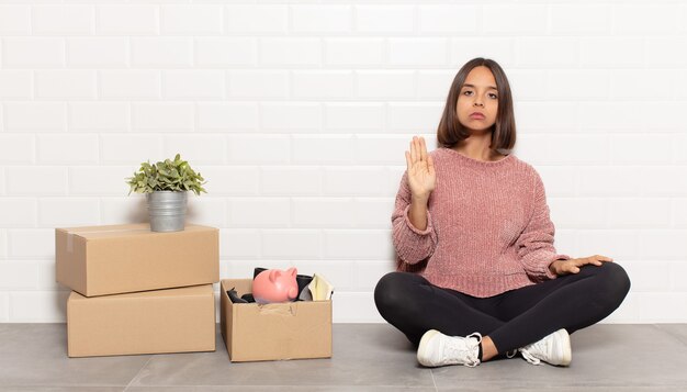 Hispanic woman looking serious, stern, displeased and angry\
showing open palm making stop gesture