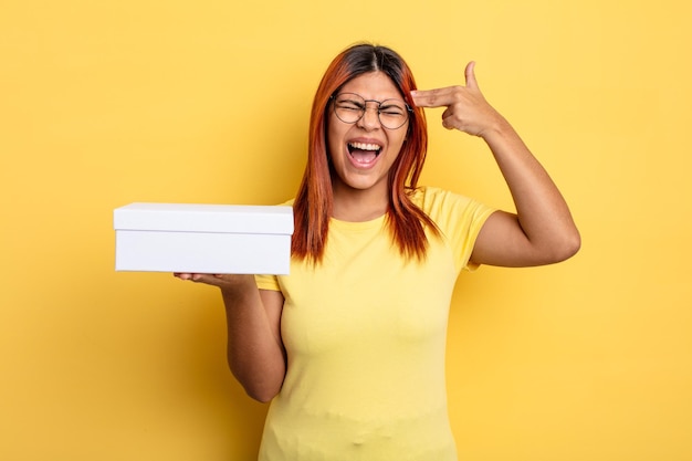 Hispanic woman looking unhappy and stressed suicide gesture making gun sign empty packaging concept