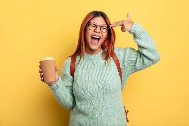 Hispanic woman looking unhappy and stressed suicide gesture making gun sign student with a coffee concept