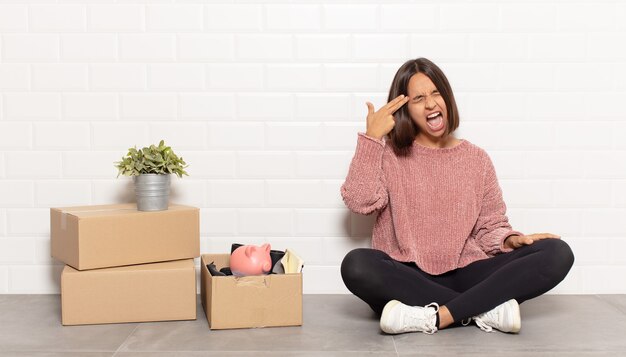 Hispanic woman looking unhappy and stressed, suicide gesture\
making gun sign with hand, pointing to head