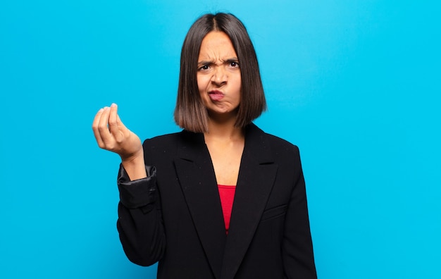 Hispanic woman making capice or money gesture, telling you to pay your debts!