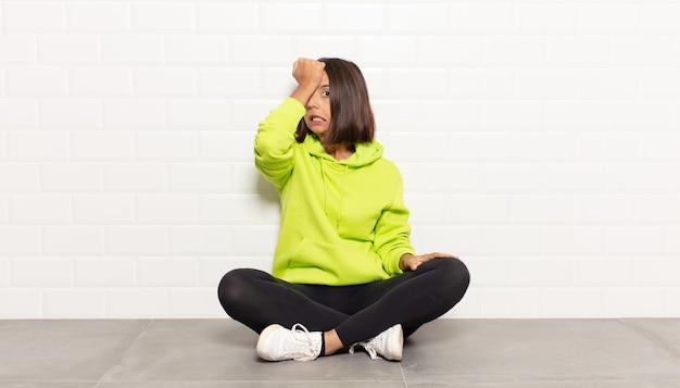 Hispanic woman raising palm to forehead thinking oops, after making a stupid mistake or remembering, feeling dumb