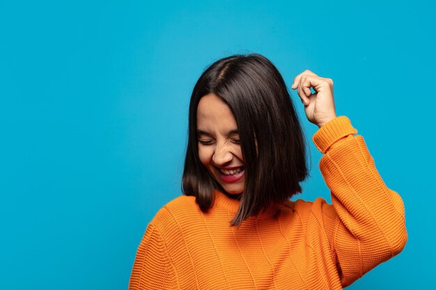 Hispanic woman smiling, feeling carefree, relaxed and happy, dancing and listening to music, having fun at a party