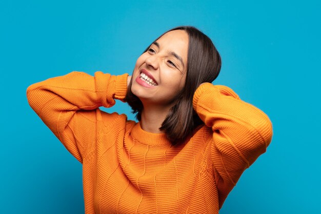 Hispanic woman smiling and feeling relaxed, satisfied and carefree, laughing positively and chilling