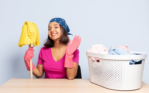 Hispanic woman smiling happily and cheerfully, waving hand, welcoming and greeting you, or saying goodbye