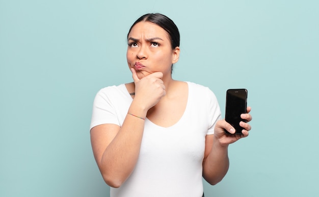 Hispanic woman thinking, feeling doubtful and confused, with different options