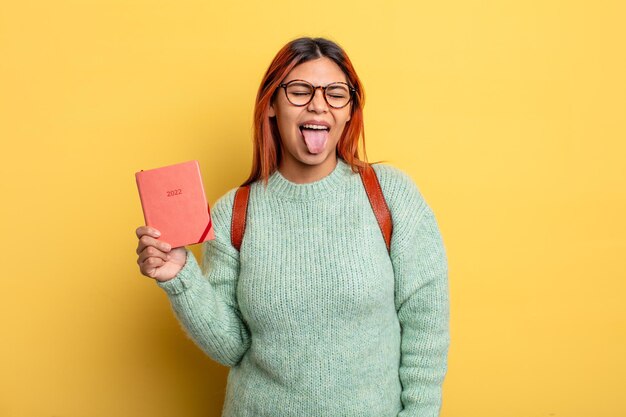 Hispanic woman with cheerful and rebellious attitude, joking and sticking tongue out. student and calendar concept