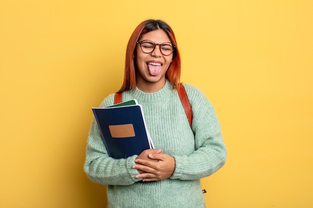 Hispanic woman with cheerful and rebellious attitude, joking and sticking tongue out. student concept