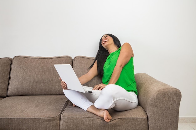 Hispanic woman with laptop laughing at joke