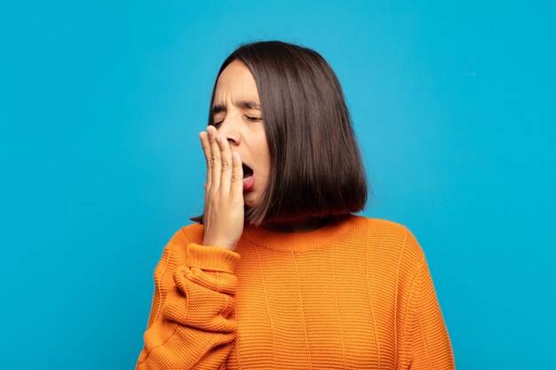 Hispanic woman yawning lazily early in the morning, waking and looking sleepy, tired and bored