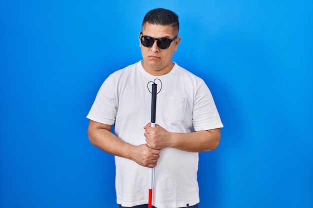 杖を持ったヒスパニック系の若い盲人男性は、問題否定的な人のために懐疑的で神経質に顔をしかめ動揺している