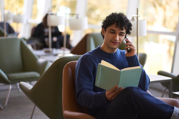 Hispanic young man talking on mobile phone planning meeting looking at his notes in the notebook