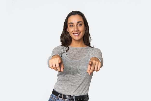 Hispanic young woman cheerful smiles pointing to front