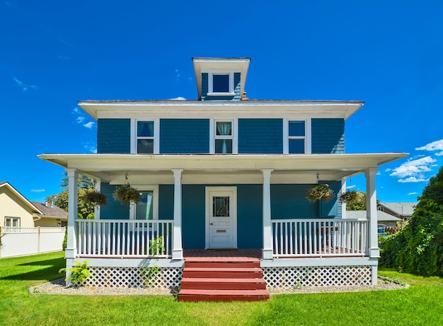 Исторический семейный дом с зеленой лужайкой впереди и фоном голубого неба