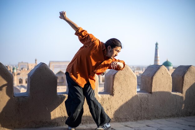 Historical buildings view on the background and a man dancing in a hypnotic style taiwanese dance historical building khiva the khoresm agricultural oasis citadel