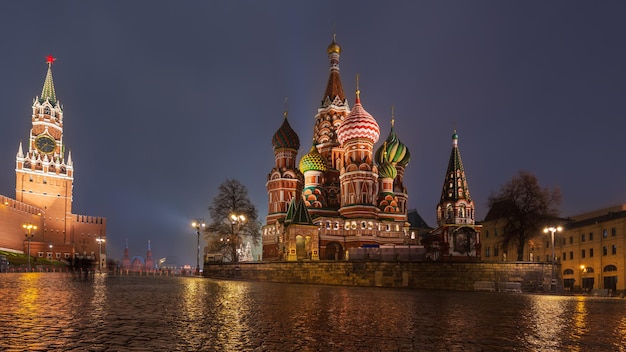 Historisch centrum van moskou met verlichte st. basil's cathedral en kremlin tower op regenachtige nacht