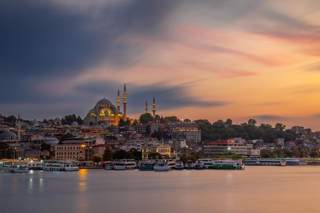 Foto historische suleymaniye-moskee bij zonsondergang en de gouden hoorn met veerboten istanbul turkije