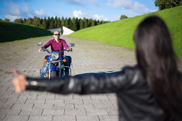 Hitchhiking concept - woman hitching man on motorcycle on the\
road