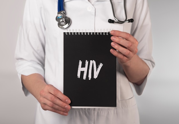 HIV acronym, inscription on paper in doctor hands.