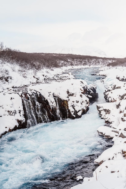 Hlauptungufoss waterfall the \'iceland\'s bluest waterfall\' blue\
water flows over stones winter iceland visit iceland hiking to\
bruarfoss waterfall