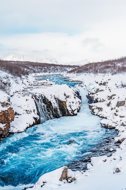 Hlauptungufoss waterfall the \'iceland\'s bluest waterfall\' blue\
water flows over stones winter iceland visit iceland hiking to\
bruarfoss waterfall