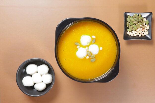 Photo hobakjuk, korean pumpkin porridge with rice balls, topping with pumpkin seeds.