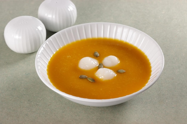 Hobakjuk, Korean pumpkin porridge with rice balls, topping with pumpkin seeds.