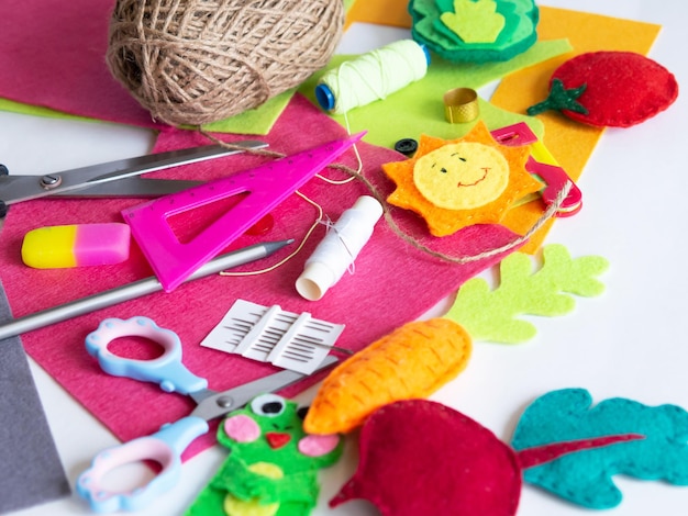 Hobby and colorful felt crafts. Workspace view. Sheets and crafts made of felt, scissors, threads and a needle for needlework.