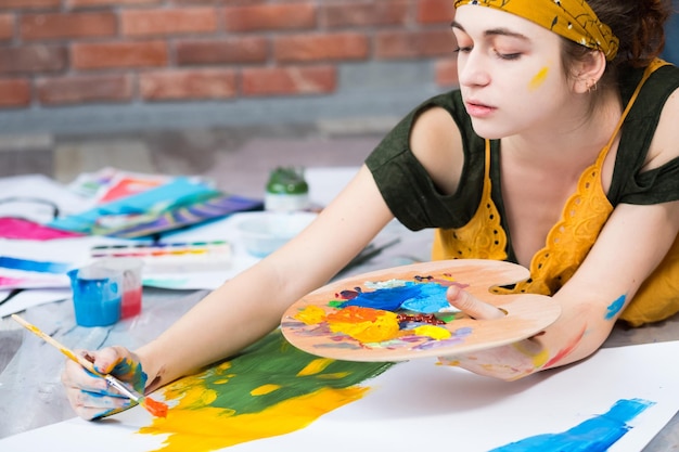 Hobby and recreation Creative female artist lying down on floor painting abstract artworks