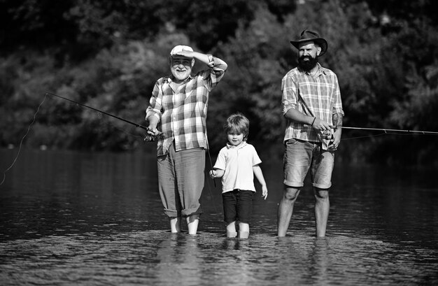 Photo hobby and sport activity man teaching kids how to fish in river happy grandfather father and