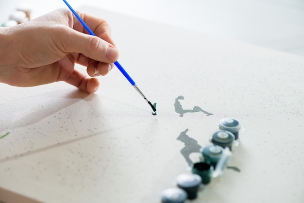 Foto hobby thuis schilderen op nummer om van bovenaf te tekenen een weergave van vrouwenhanden die een penseel met verf vasthouden.