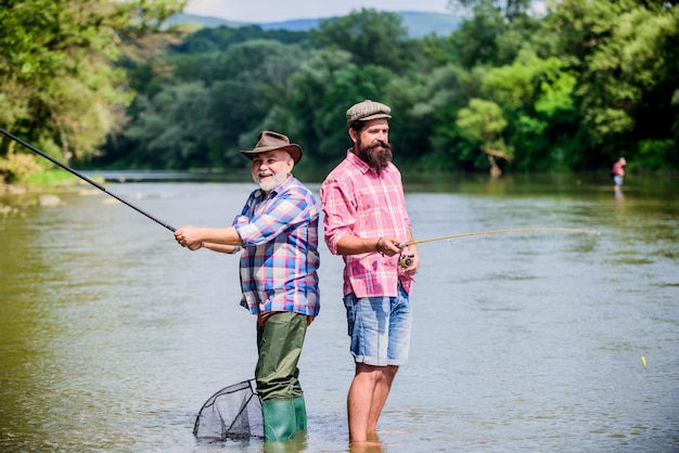 hobby zaken twee gelukkige visser met hengel en net hobby en sport activiteit forel aas man vriendschap familie bonding zomer weekend volwassen mannen visser vader en zoon vissen