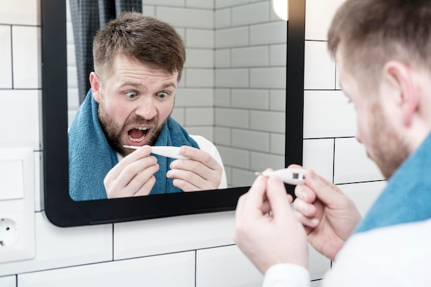 hocked man holding a thermometer in hands and is scared by his high temperature