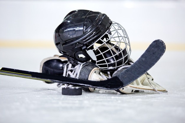 Хоккейный шлем, шайба, клюшка и коньки на хоккейной площадке