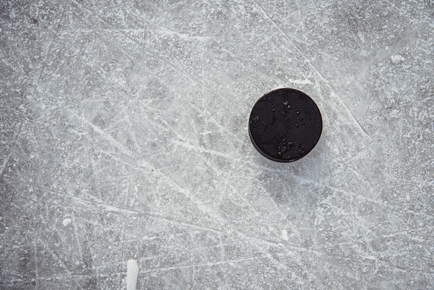 Photo hockey puck lies on the snow close-up